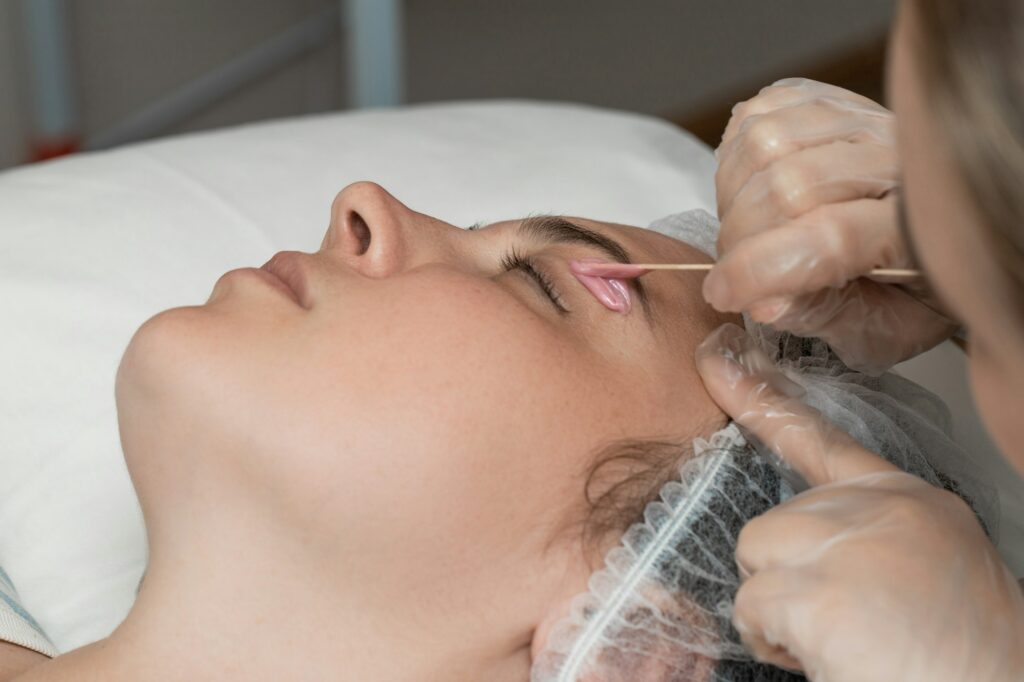 Hand of cosmetologist applying wax paste on armpit