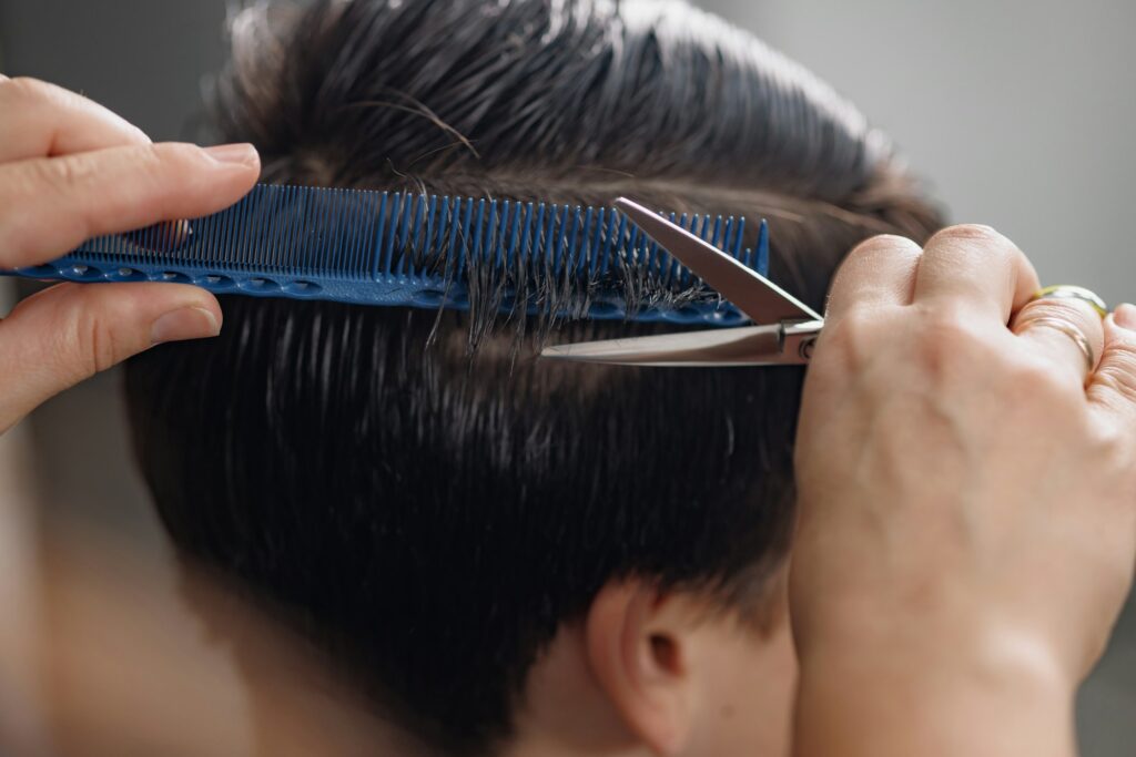 professional hairdresser cuts a guy's hair in a beauty salon, men's haircuts close-up